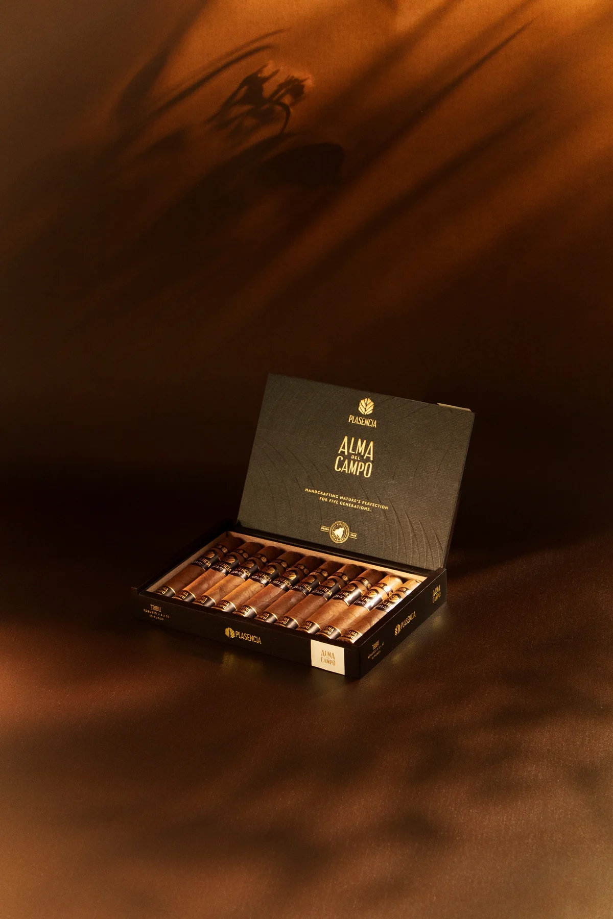 An open box of Alma del Campo on brown cloth, leaf shadows across it
