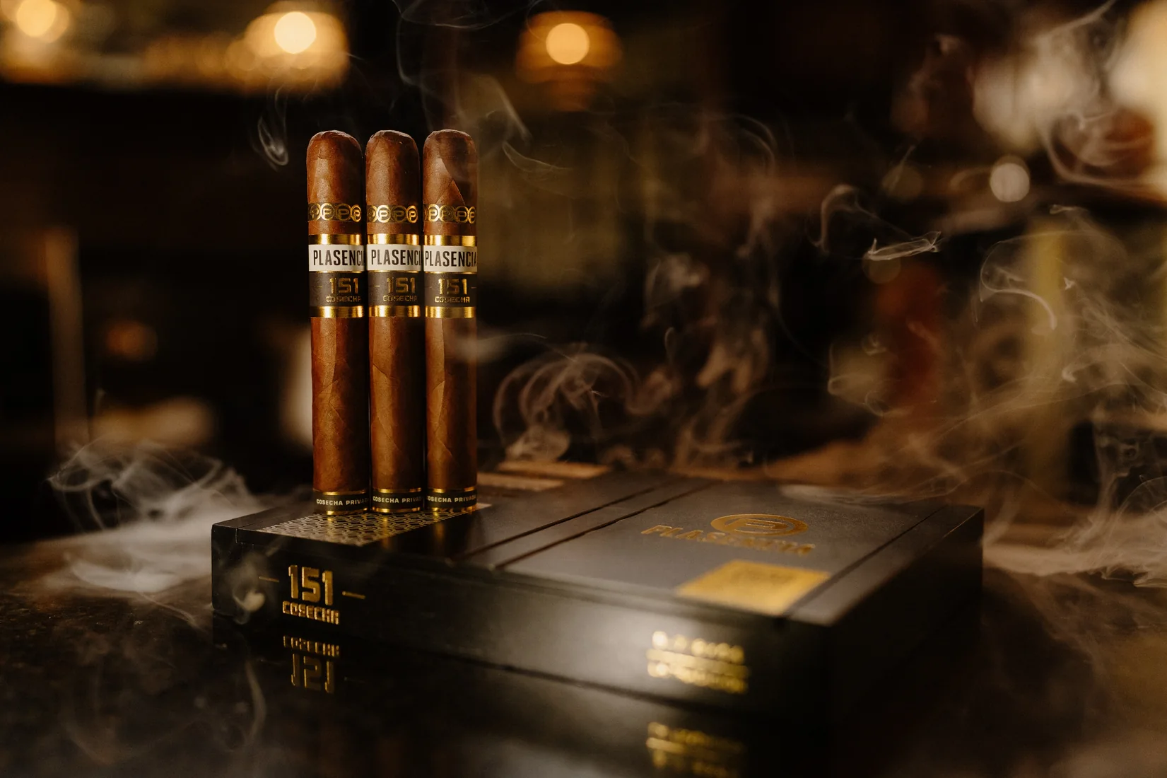 Three Cosecha 151 cigars standing on a closed box, smoke drifting around them