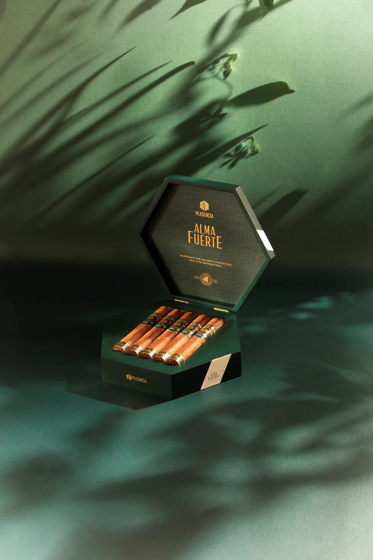 An open box of Alma Fuerte on green cloth, leaf shadows across it